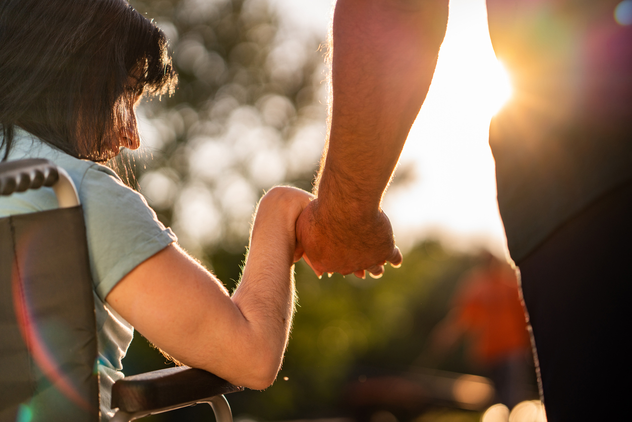 Close up women on a wheel chair holding mens hand